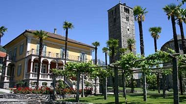 Giardino con palme e edificio storico presso Villa San Quirico.